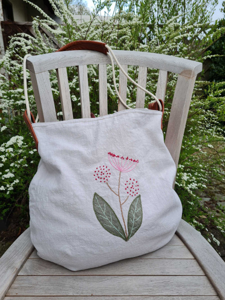 Beuteltasche aus cremefarbenen Leinen bestickt mit Blumenmotiv.