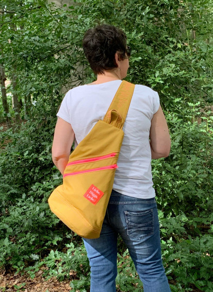 Gelber Crossbag-Rucksack mit neonfarbenen Reißverschlüssen und Liebe, Digga, Liebe Etikette.